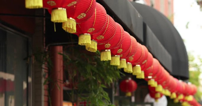 Many chineese traditional lantern lights hanging in front of a shopping strip. Beautiful shot with aluminum reflections in 4k slowmotion.mov