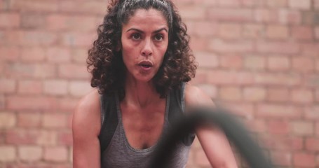 Closeup mid adult female working out with battle ropes