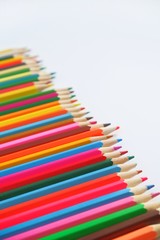Mixed colored pencils on a white background for learning to draw in school laid out in a row .  With selective focus, copy spase for text.