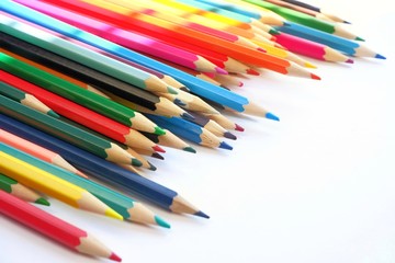 The sun's rays fall on the colored pencils lying on a white background. Color Therapy Concept.Copy space for text, with selective focus.
