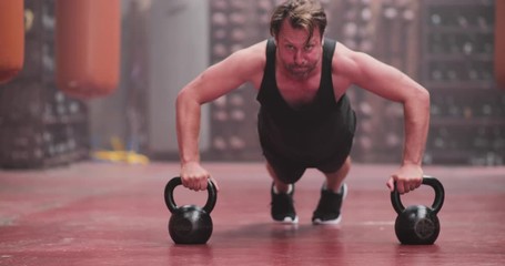 Adult male doing dumbbell pushups at the gym