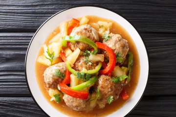 Meatballs cooked with fresh pineapples and vegetables in a sweet and sour sauce closeup on a plate. horizontal top view