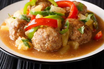 Serving of meatballs with fresh pineapples and bell peppers in sweet and sour sauce close-up on a plate. horizontal