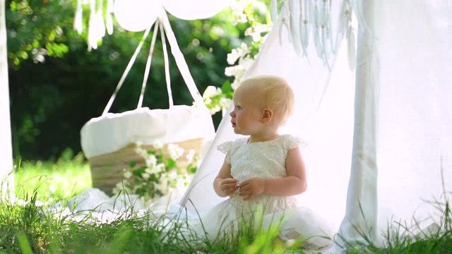 A baby is plays with beads and claps her hands on the birthday photosession.