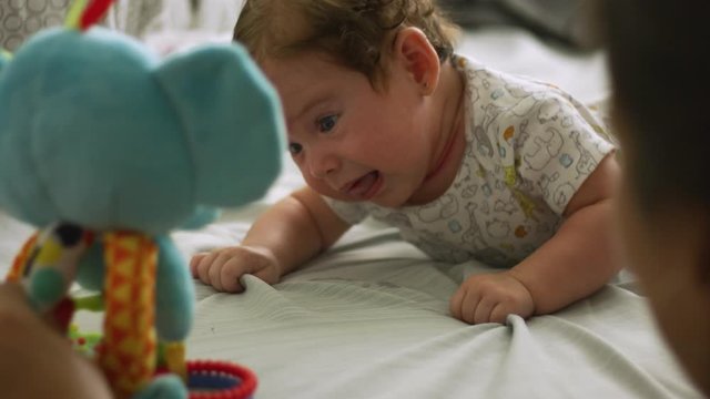 Slow motion of mother moving toy in front of baby during belly time