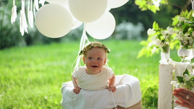A baby sits in the basket with a hot air balloons in the summer park