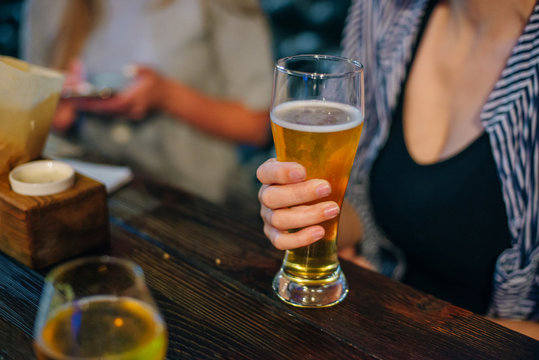 leisure, drinks, degustation, people and holidays concept - close up woman hand holding glass of draft lager beer