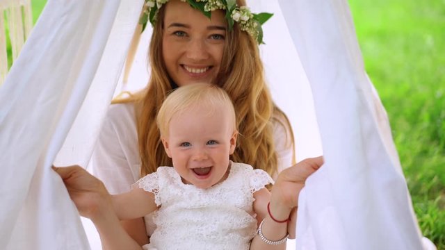 A mother plays hide-and-seek game with her daughter in the wigvam