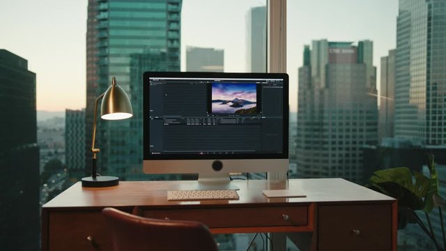 workplace with view on city, Downtown LA in background, big screen of computer, editing photos, work corner