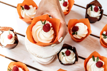 Holiday muffins with cream and berries in individual orange paper packaging.