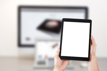 Mockup image of a woman holding a tablet and in the background a desktop computer with a laptop. Blank screen with copy space.