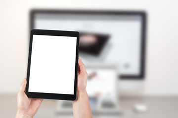 Mockup image of a woman holding a tablet and in the background a desktop computer with a laptop. Blank screen with copy space.