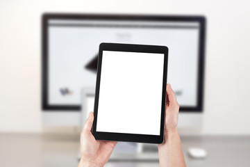Mockup image of a woman holding a tablet and in the background a desktop computer with a laptop. Blank screen with copy space.