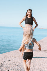 Fototapeta premium Little cute girl running to fit mom on beach, healthy lifestyle, sport family