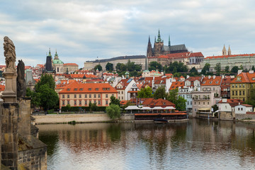 Obraz premium View of statues on the Charles Bridge (Karluv most), Mala Strana District (Lesser Town), Prague (Hradcany) Castle and St. Vitus Cathedral in Prague, Czech Republic, on a cloudy day.
