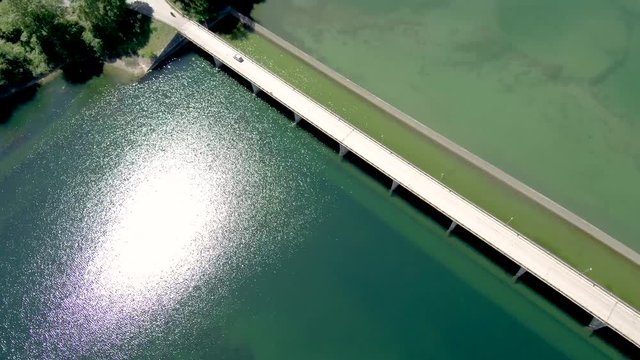 Aerial view of Aliakmonas river with car bridge in a plain with crops, Aliakmonas river, Veria Greece, moving up and forward by drone