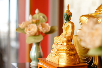 The statue of the Emerald Buddha covered the golden cloth on the wooden table in the red room.