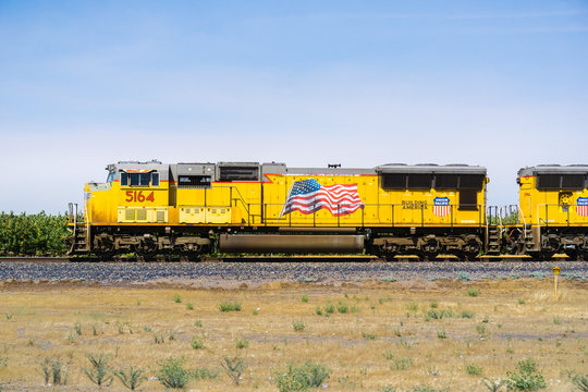 July 17, 2018 Madera / CA / USA - Union Pacific train engines displaying the American flag travelling on the side of the highway