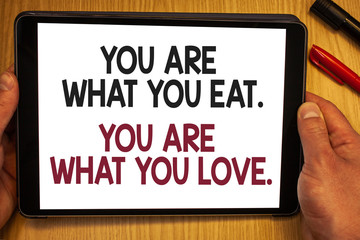 Handwriting text You Are What You Eat. You Are What You Love.. Concept meaning Start to eat healthy food Hand hold showing colorful letters black marker red pen timber carrel