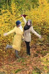 Naklejka na ściany i meble two girls spread their arms, enjoy life in a yellow autumn park, the concept of family relations, generations