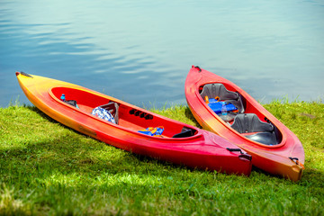 Red canoe lying in the grass on the lake 