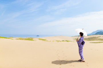 絞り染めの浴衣を着て砂丘に立つ女性