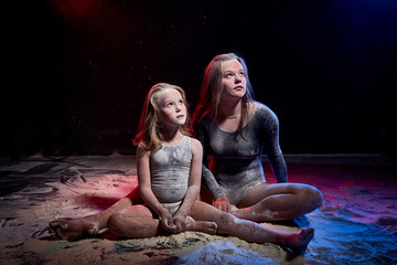 Two sisters in black studo with red and blue light during photoshoot with flour