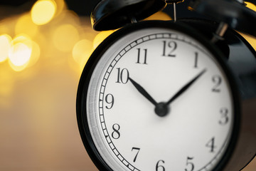 Fototapeta na wymiar Close up of retro alarm clock on blurred Christmas background with bokeh