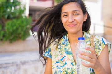 Young indian woman driking water in the street