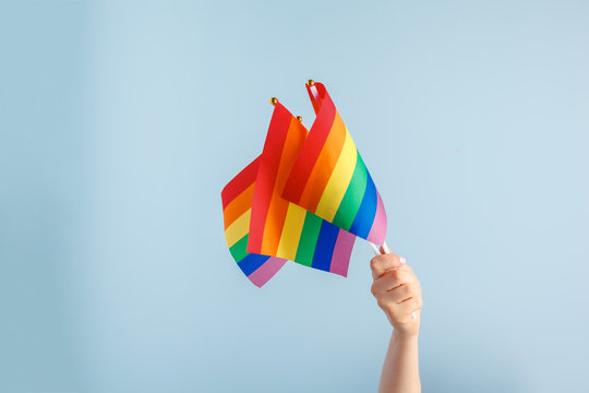 Gay flags in women's hand on grey background