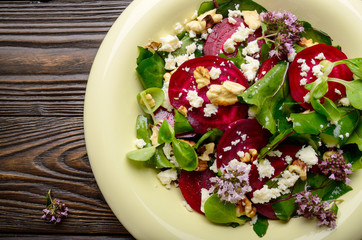 Top view at mediterranean roasted beet salad with walnuts feta cheese oregano and mash leaves on wooden table