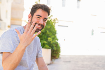 Young man doing number five gesture in the street