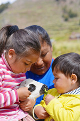 Happy indigenous South American family taking care of a little lamb.