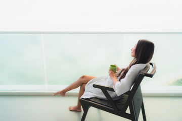 Beautiful Portrait young asian women holding coffee cup at outdoor balcony with sea ocean view