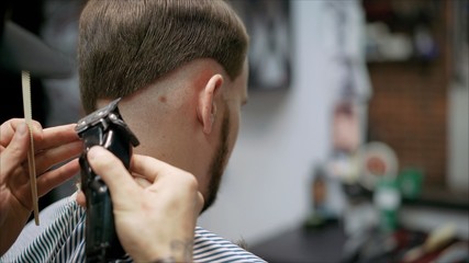 Men's haircut in barbershop. Master barber does a haircut to the client. Work with scissors and clipper. Close-up of the workflow