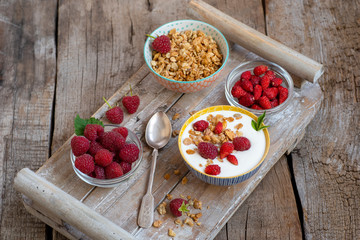 Bowls with berries, yogurt, granola on an old wooden table.