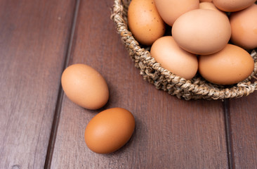 Close up of organic raw chicken eggs in bamboo basket with two eggs place on brown wooden floor background