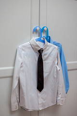 two shirts hanging on the cabinet door ready to use, men's classic clothes, black tie difficult choice, white and blue, school, work, business, education, inevitability