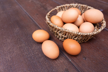 Close up of organic raw chicken eggs in bamboo basket with three eggs place on brown wooden floor background