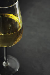 Obraz premium Transparent bottle of white dry wine on the table. White wine glass on a wooden background.