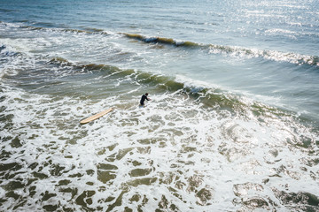 Aerial view on surfer in the sea, surfer catching waves in baltic sea.