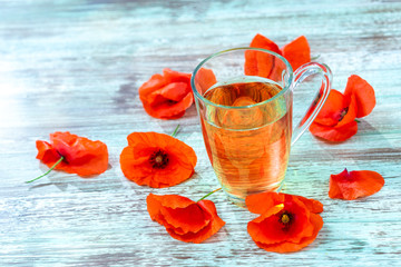 Red poppy flower tea drink in glass mug on wooden background. Concept of healthy eating.