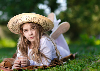 Young girl with hat lying in grass