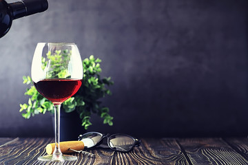 A glass of red dry wine on the table. Dark bottle and glass of wine.