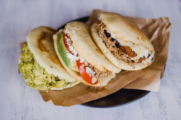 Arepa, typical food from Venezula and Colombia, on a white background ready to eat. Arepas are filled with desmechada meat, avocado, cheese and beans