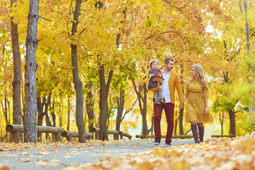 Family walking in the park in yellow autumn.