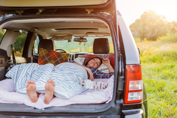 woman sleeps comfortably her car Luggage compartment nature summer under blanket. concept caravanning free travel for weekend.