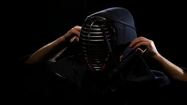 Skilled Kendo warrior is tying the lacing on his helmet. Slow motion
