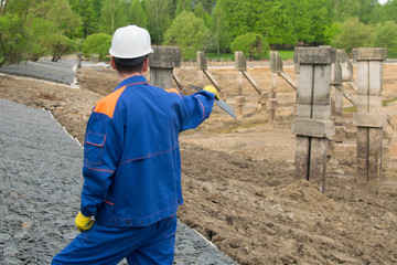 worker in blue uniform and white helmet, with a tablet in his hands, exploring the area under construction