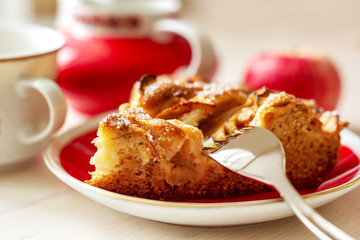 A piece of apple pie on the plate with fork, fresh apple and cup of coffee close up	